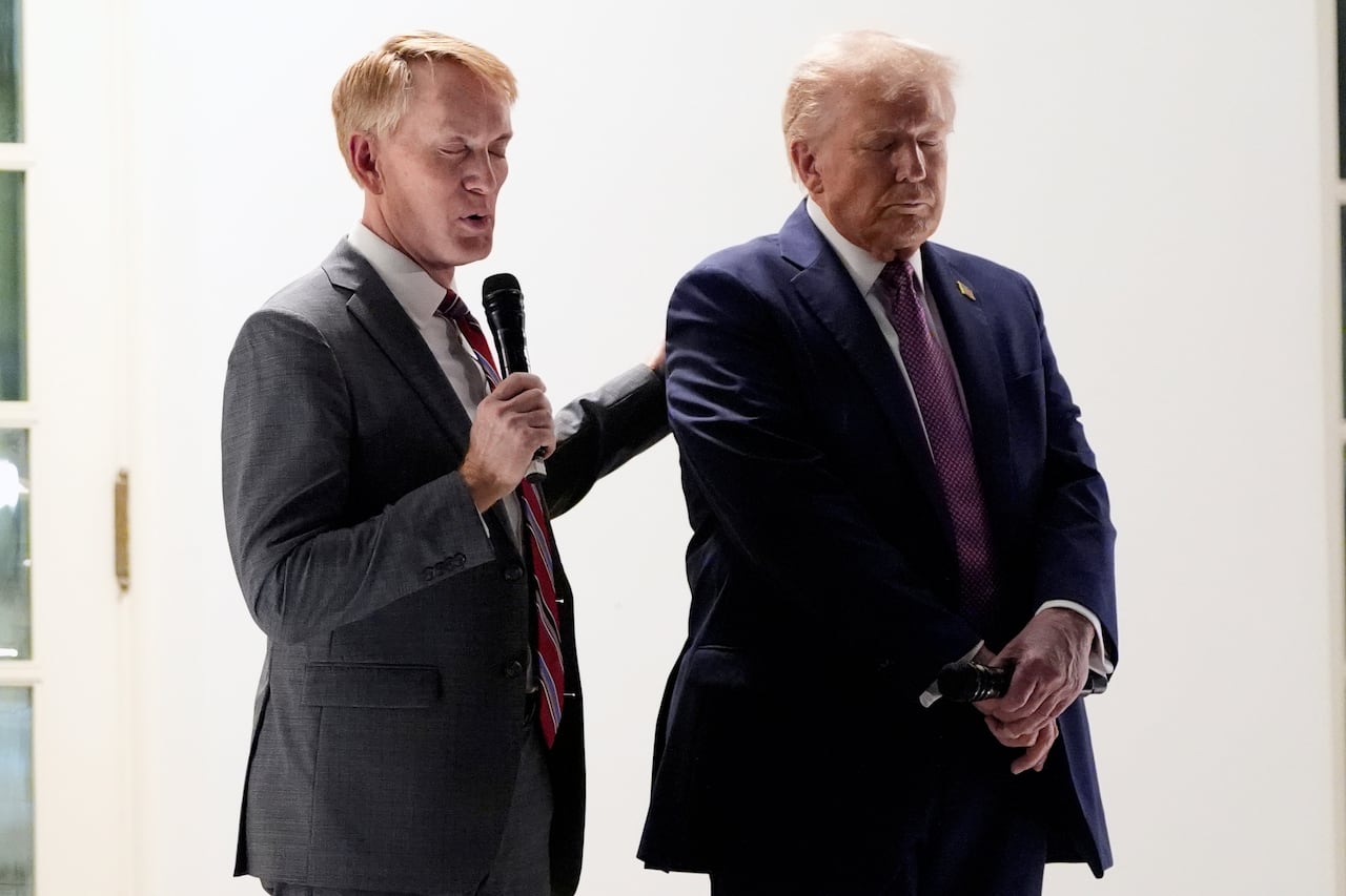 Two clean men based on a suit and tie are shown. One person has their hand on each other's shoulder and closes their eyes.