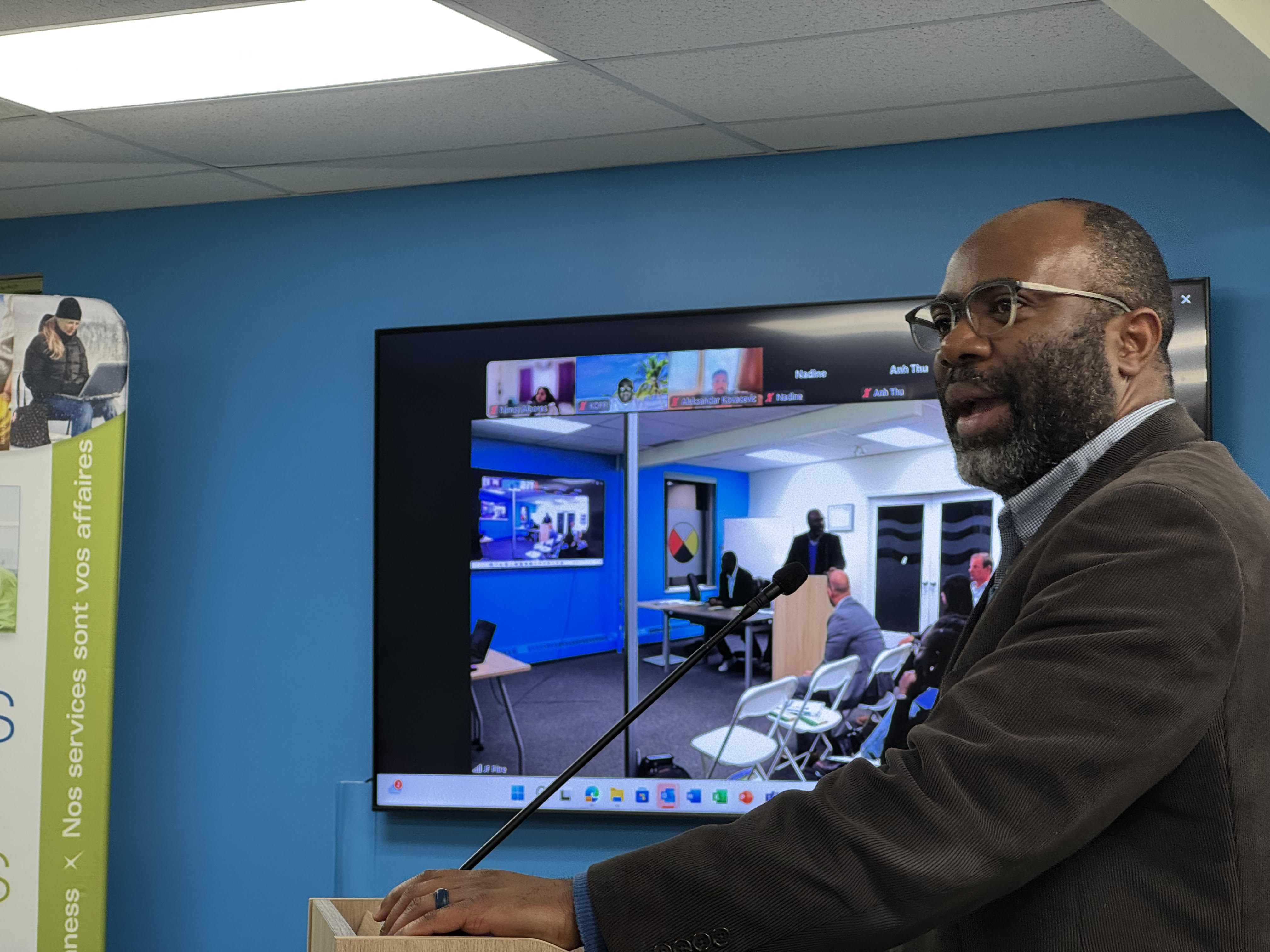 François Afane is the executive director of the Conseil de développement économique des Territoires du Nord-Ouest (CDETNO). The non-profit held its 2025 annual general meeting in Yellowknife on Oct. 9, 2025. A man speaking at a podium in a blue-walled room.