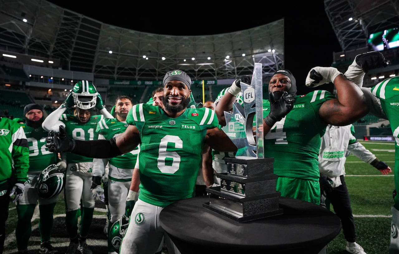 A group of men in green T-shirts pose for a photo with a trophy on a black table. 