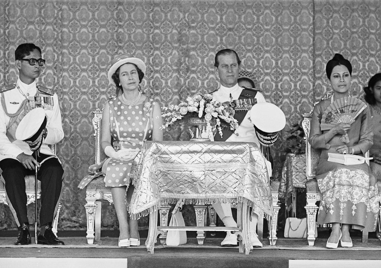People are sitting on chairs in this black and white photo.