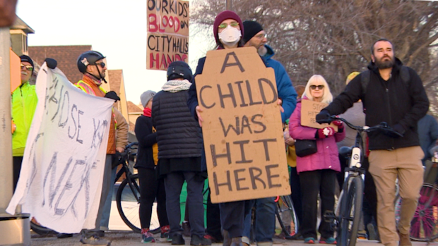 Rally on street with people holding signs "a child was hit here"