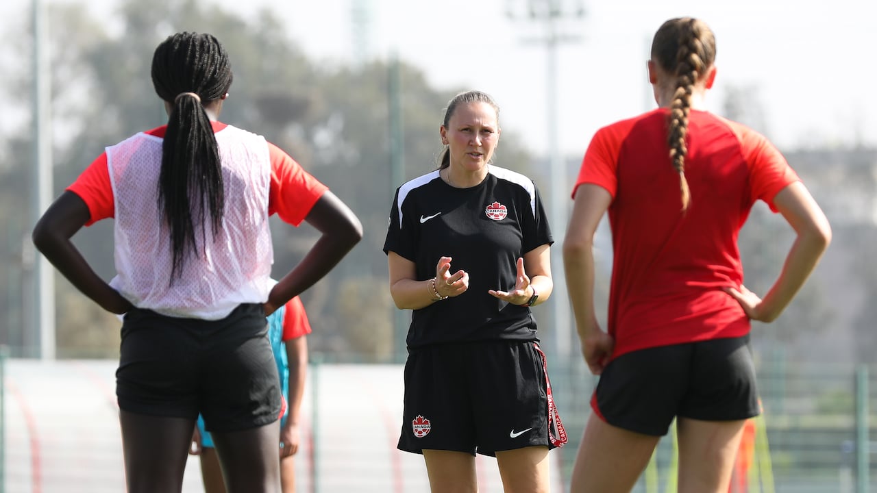 A women's soccer coach talks to players representing Canada.