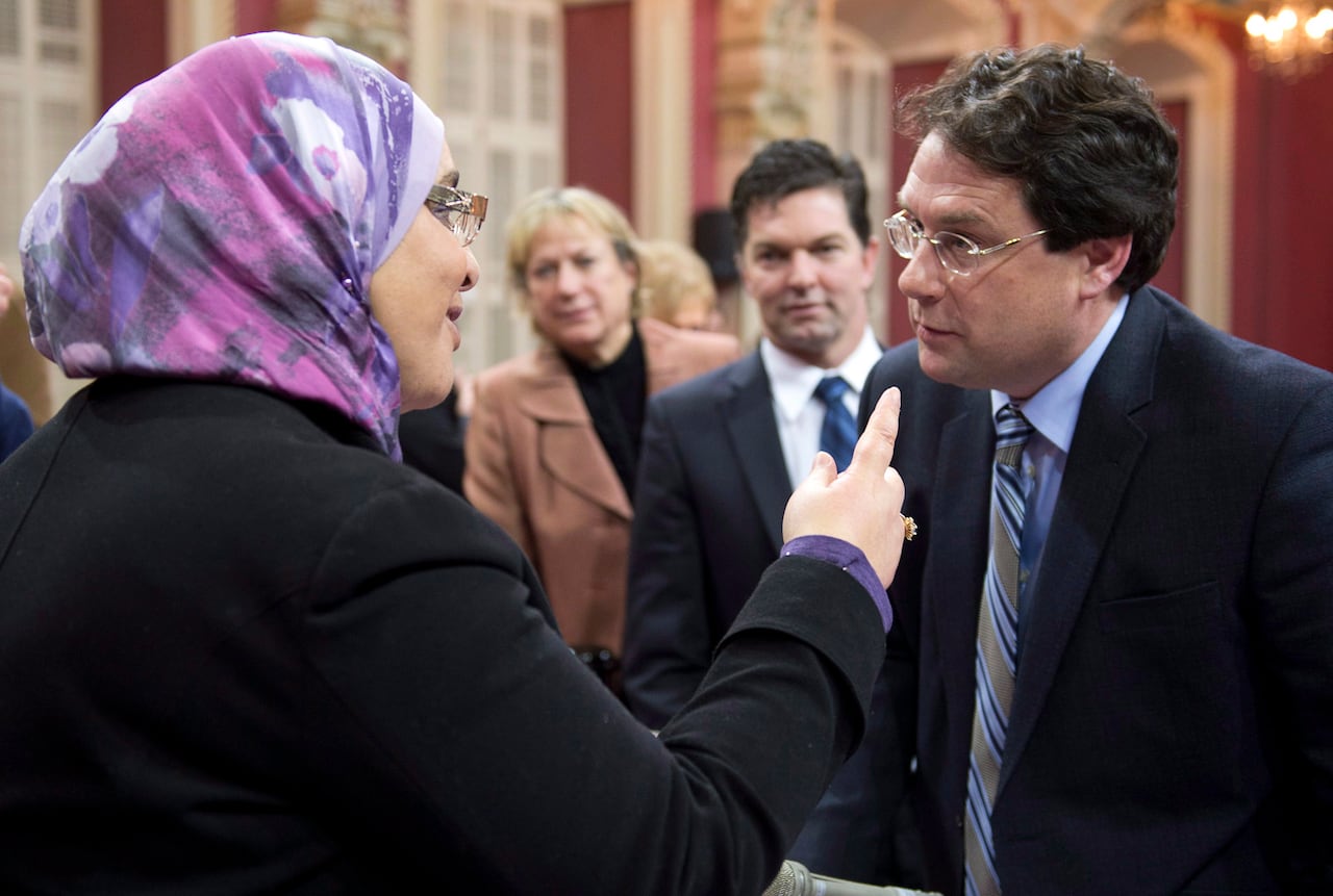 Cabinet minister Bernard Drainville talks to a woman wearing a hijab in the National Assembly