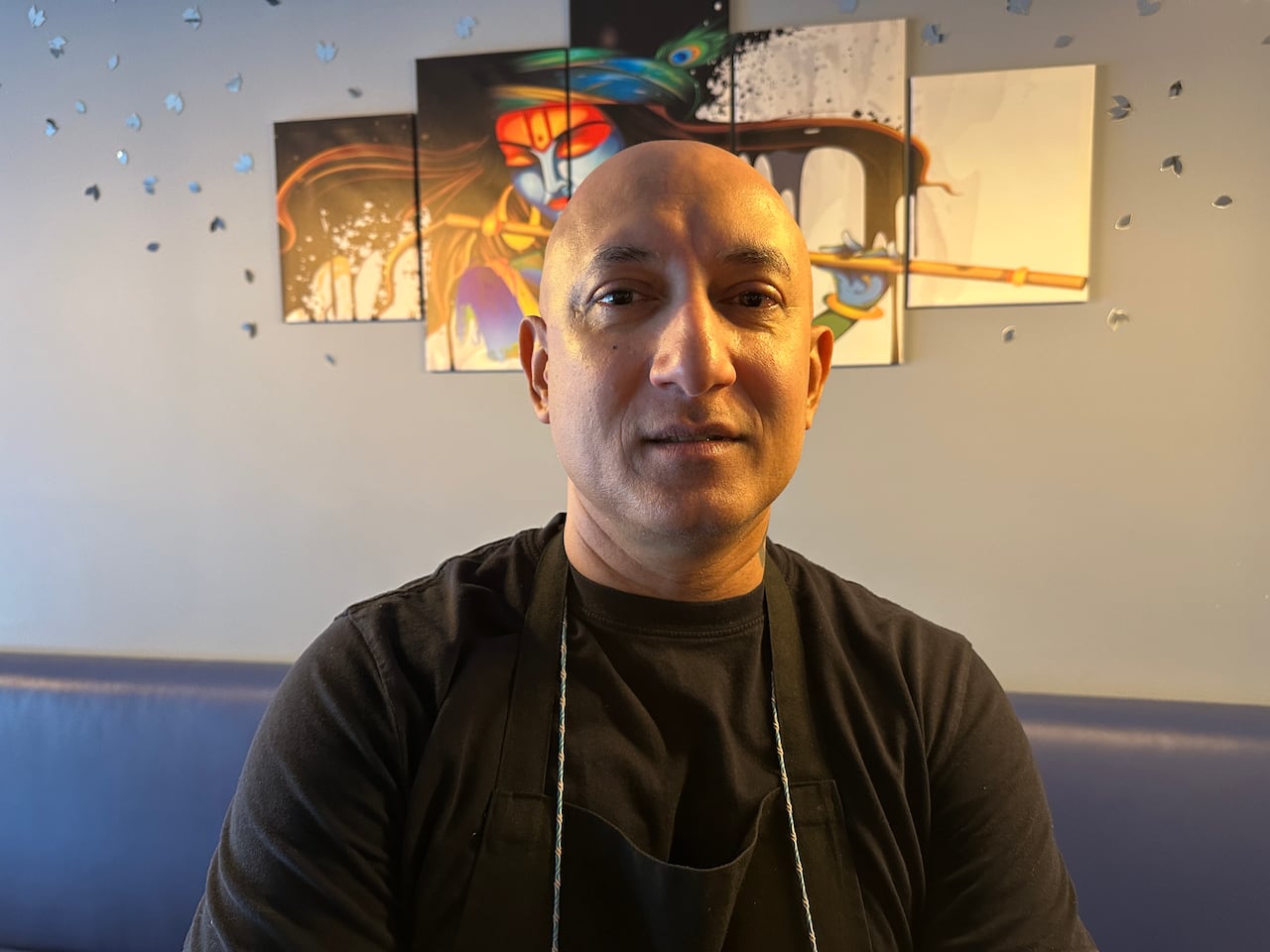 Un hombre calvo frente a una obra de arte.