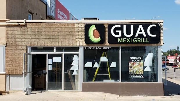 A sign on a building says Guac Mexi Grill and a poster in the window says "Coming Soon."