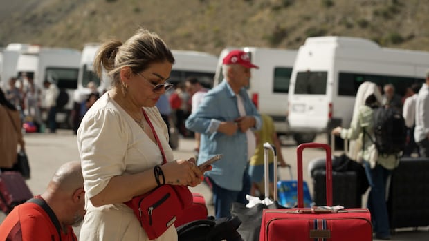 People trekked overland in Iran to reach a border with Turkey. A woman looks at her phone in a parking lot.