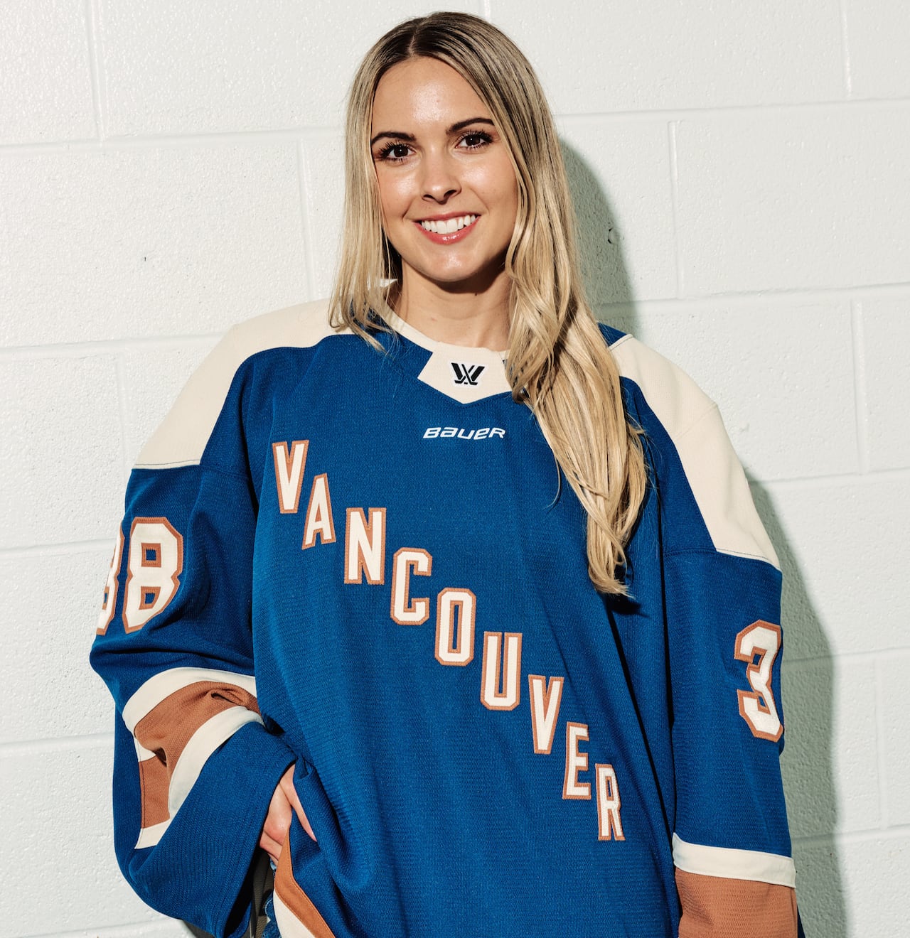 A woman wears a hockey jersey with Vancouver on the front.