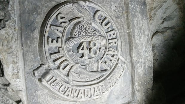 a carving on a wall lit up, saying 15th Canadian Battl.
