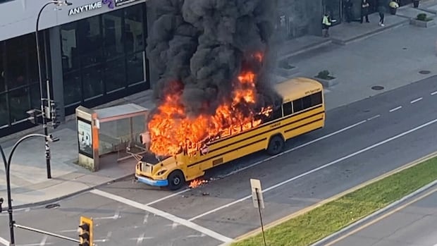A school bus engulfed in flames on a city street