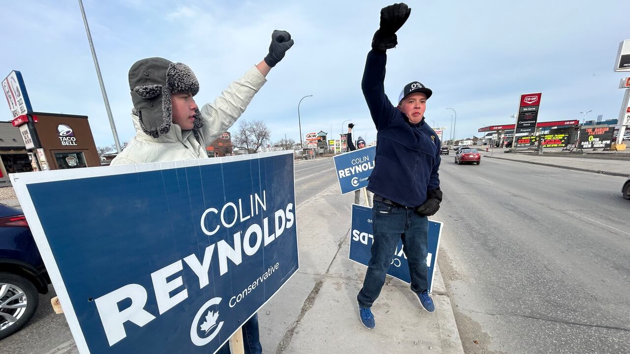 Two young men holding predetermination  run  signs basal   connected  a sidewalk with their fists successful  the air.