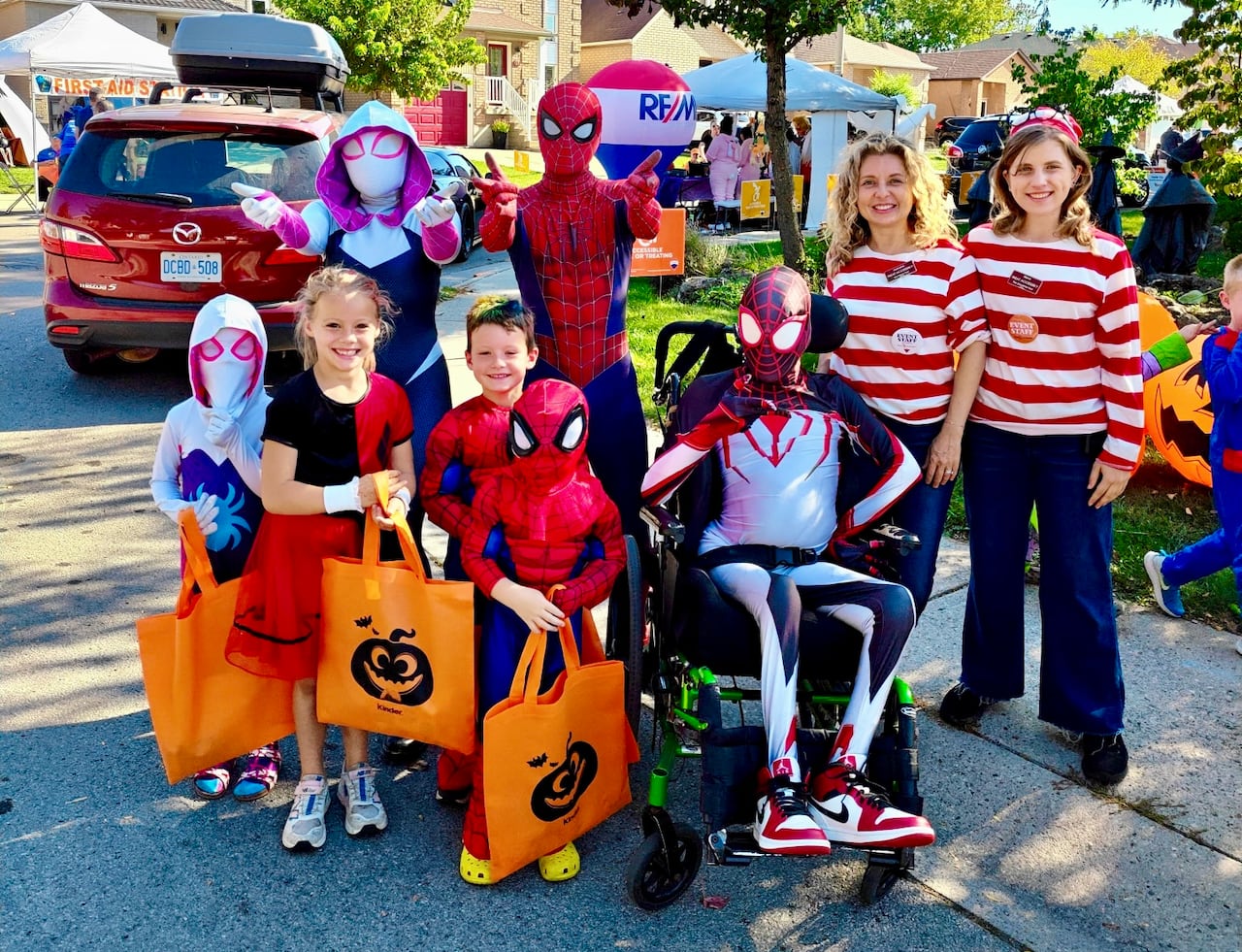 Two people dressed as Waldo pose with six others, most in Spider-Man costumes on a suburban city street.