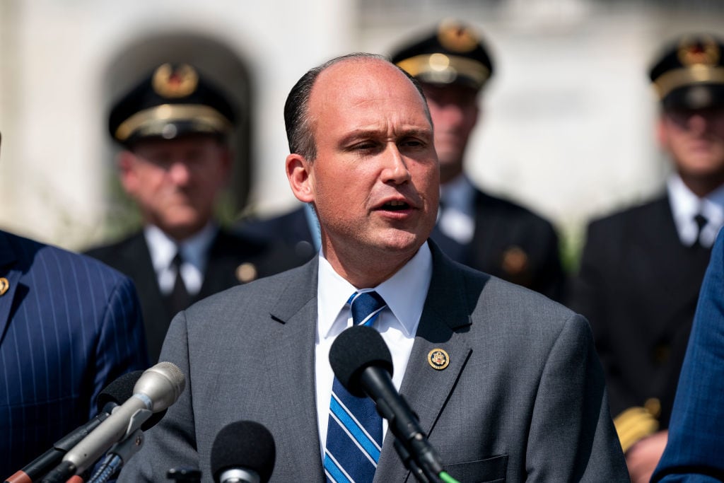 A man speaks out with military personnel behind him.