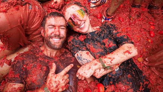 SPAIN-CULTURE/TOMATO FIGHT A man and a woman smile widely as they lie in a pile of smashed tomatoes.