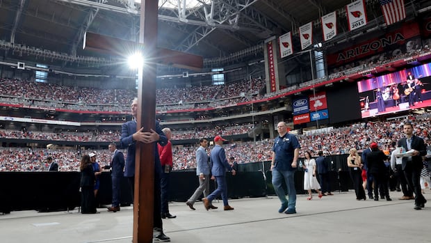 A person holds a cross ahead a memorial service for slain conservative commentator Charlie Kirk at State Farm Stadium