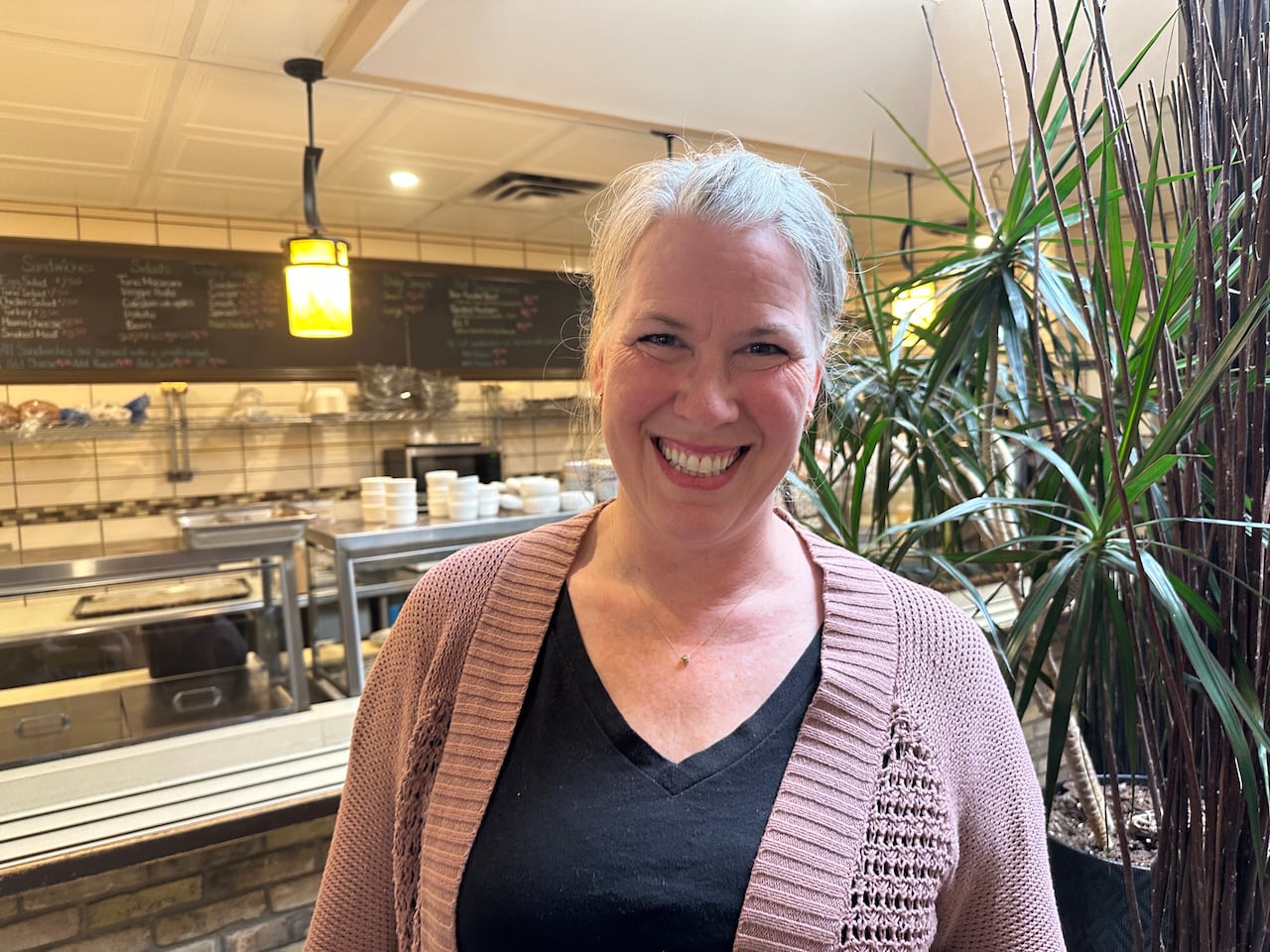 Una mujer sonríe cerca de un mostrador de comida.