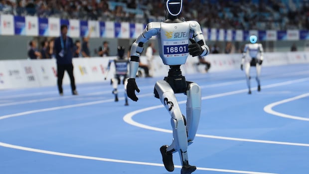 Humanoid robots compete in the 400m race during the 2025 World Humanoid Robot Games at National Speed Skating Oval on Aug. 15, 2025 in Beijing, China A humanoid robot sprints across a track in Beijing, with other robots in the background.