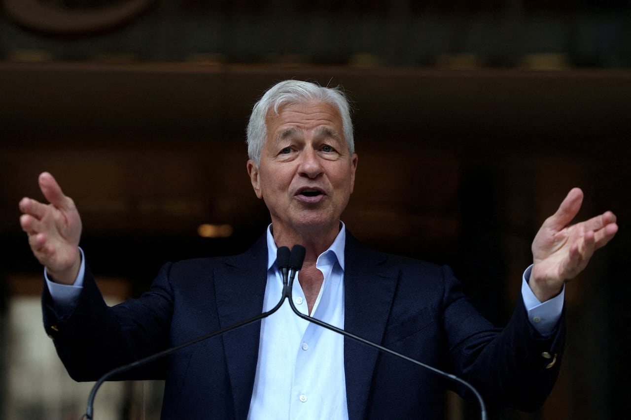 A man wearing a suit jacket gestures while speaking.