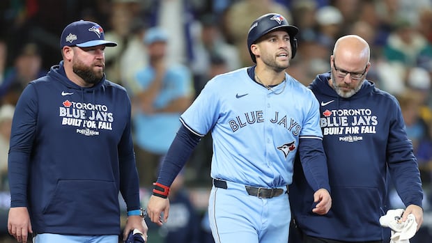 A man in a blue baseball uniform walks between two other men.