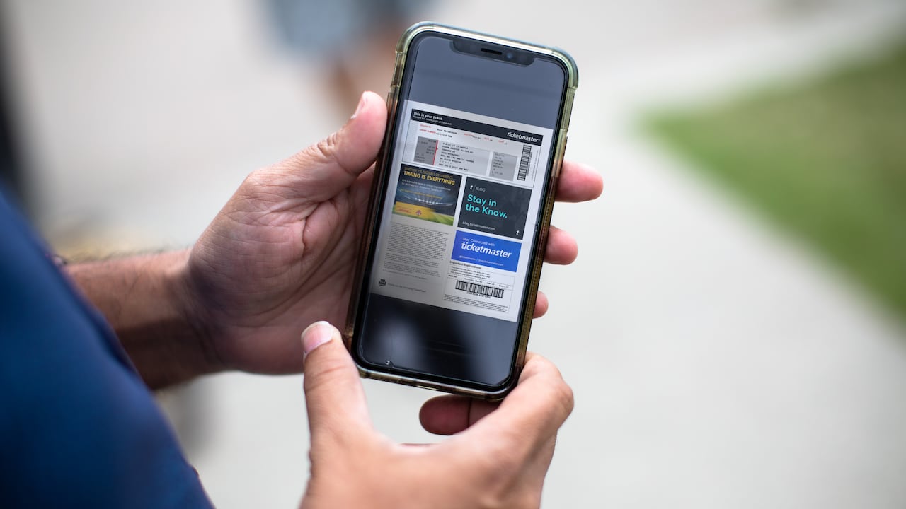 Person holds a phone with their Ticketmaster ticket on display.