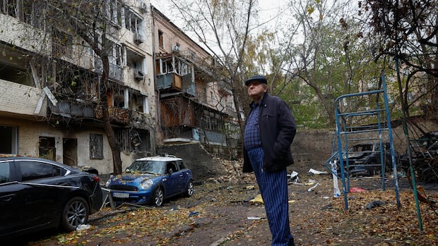A resident looks at his apartment building, which was damaged during an overnight Russian drone strike on Kyiv on Wednesday. A man in a cap looks at apartment buildings, which have been severely damaged by a drone strike.