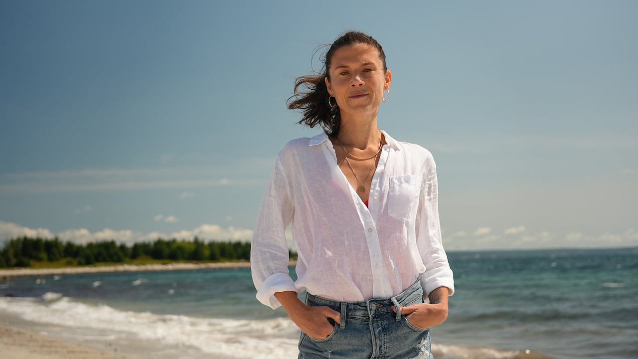 A happy-looking woman stands on a beach