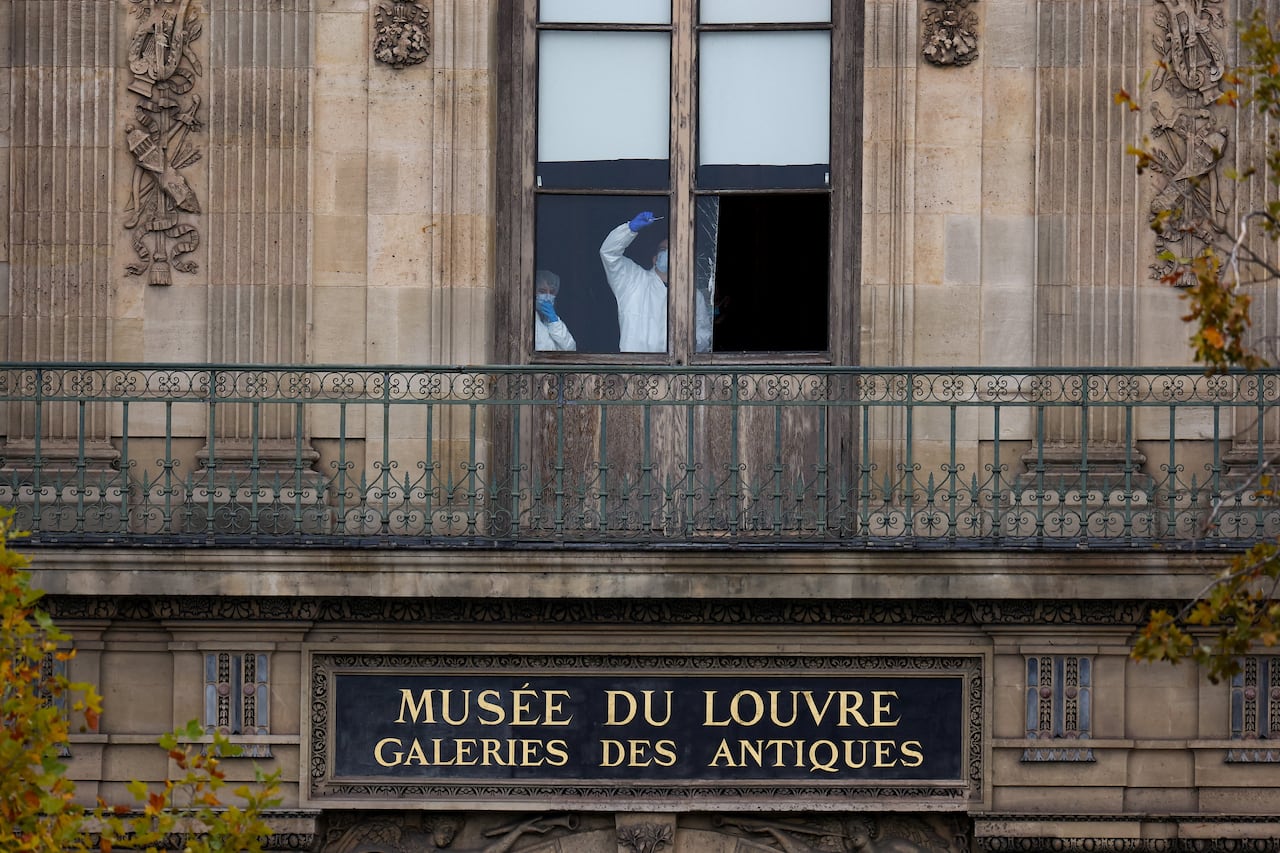 Forensic experts in personal protective equipment examine the window.