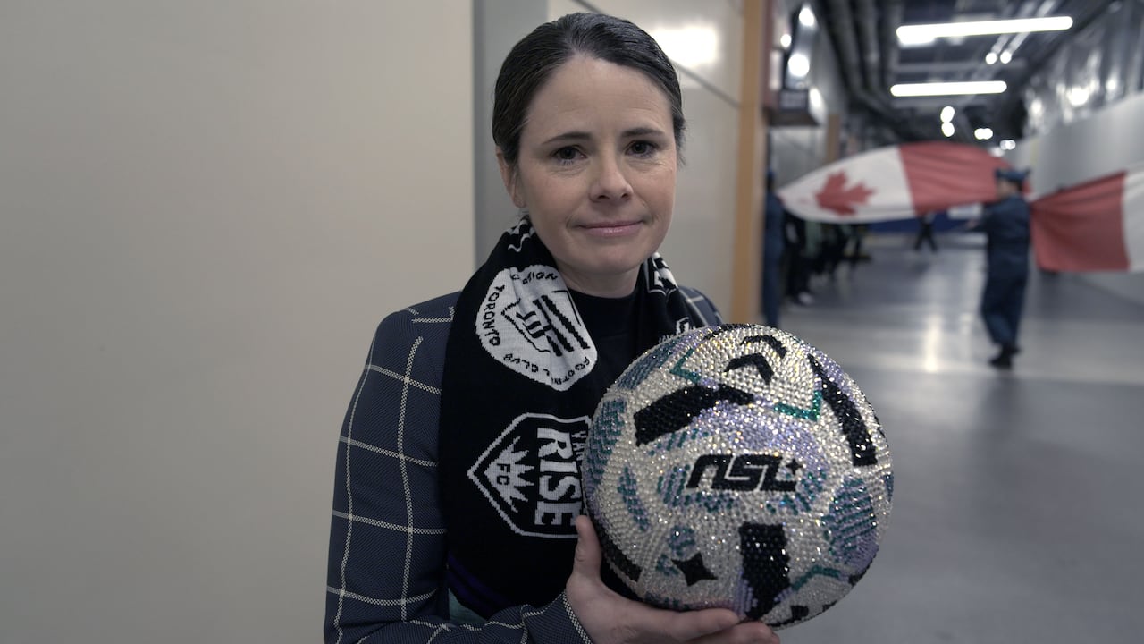 A woman wearing a scarf holds a glittering soccer ball.