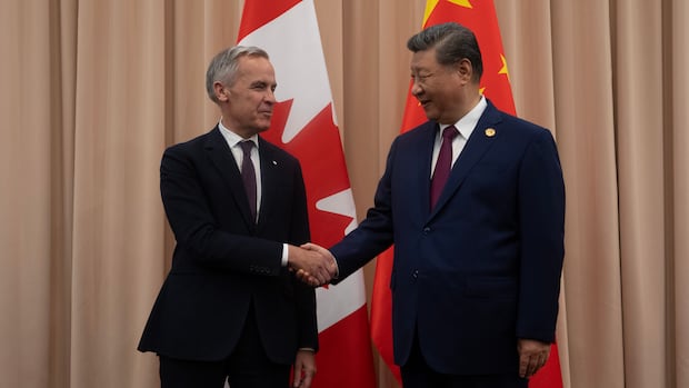 Prime Minister Mark Carney shakes hands with Chinese President Xi Jinping at the start of a meeting in Gyeongju on Friday. Carney has faced pressure from some premiers to drop the 100 per cent tariffs on Chinese electric vehicles. Two men in suits shake hands and smile against a backdrop of two flags
