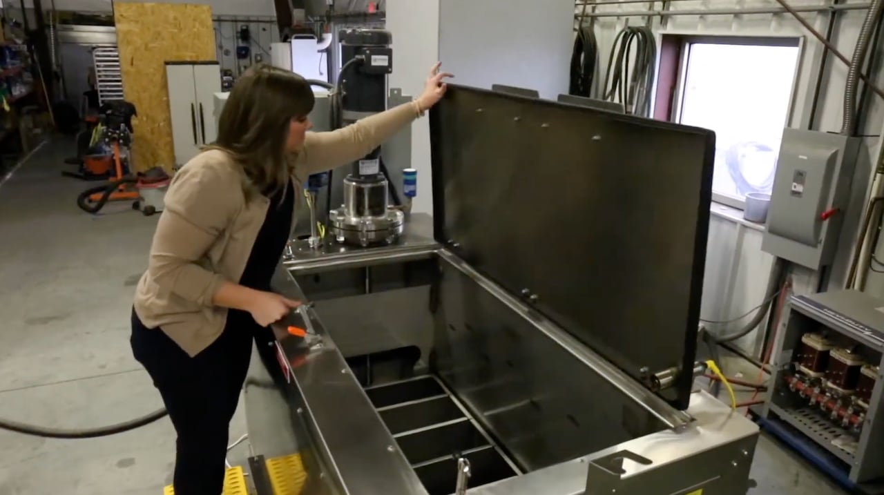 woman lifts lid of rectangular metal container