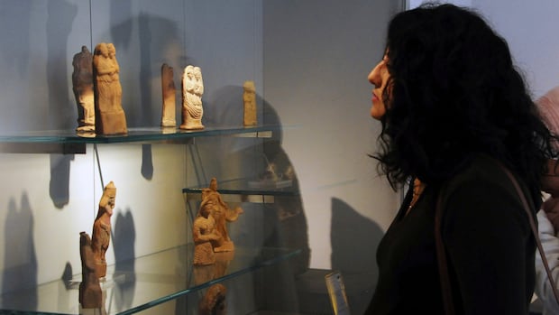 In this photo released by the Syrian official news agency SANA, a visitor looks at ancient artifacts during the reopening ceremony for Syria's National Museum in Damascus on Oct. 28, 2018. A woman looks at artifacts at a museum.