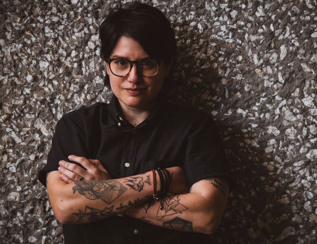 A woman looks at the camera with her arms crossed