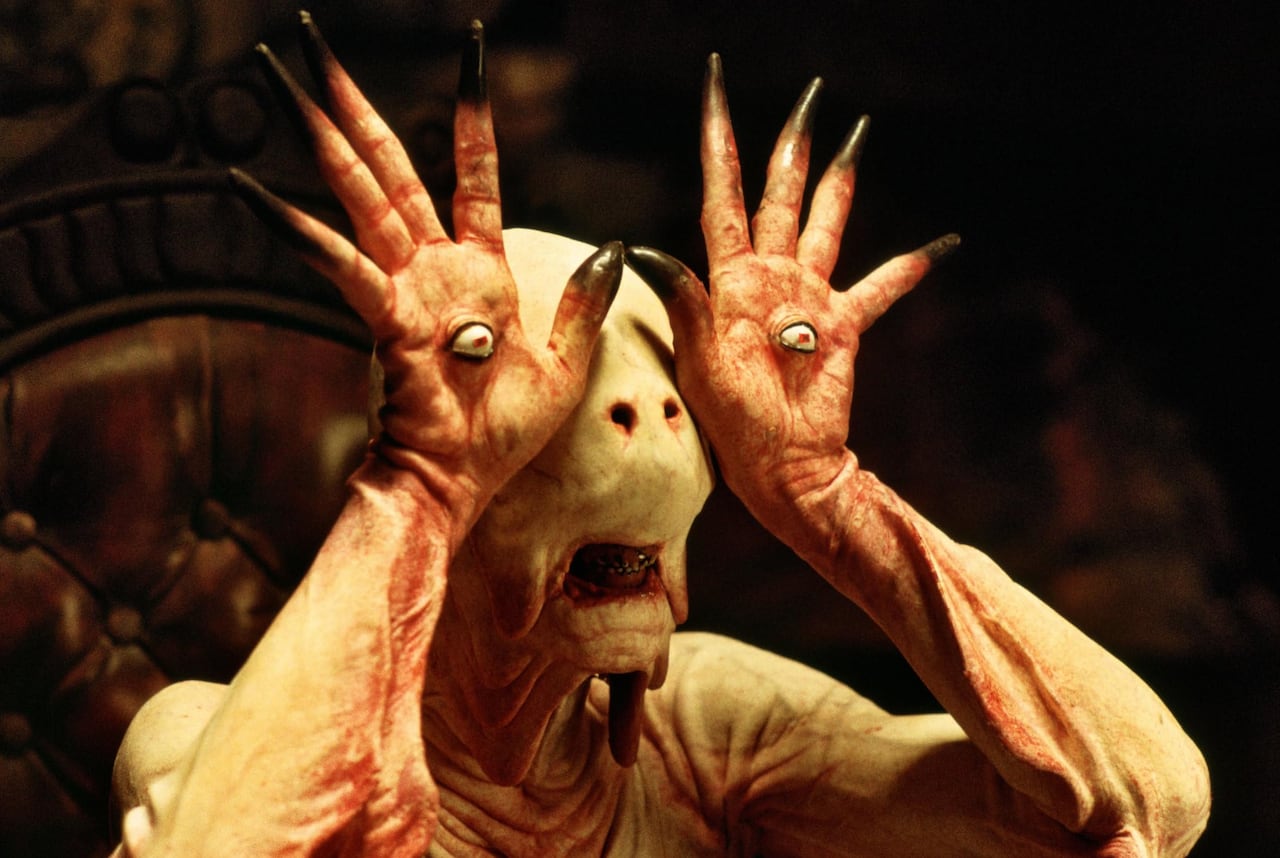 A monster with an eyeball embedded on the palms of its hands, holding its hands in front of its face.
