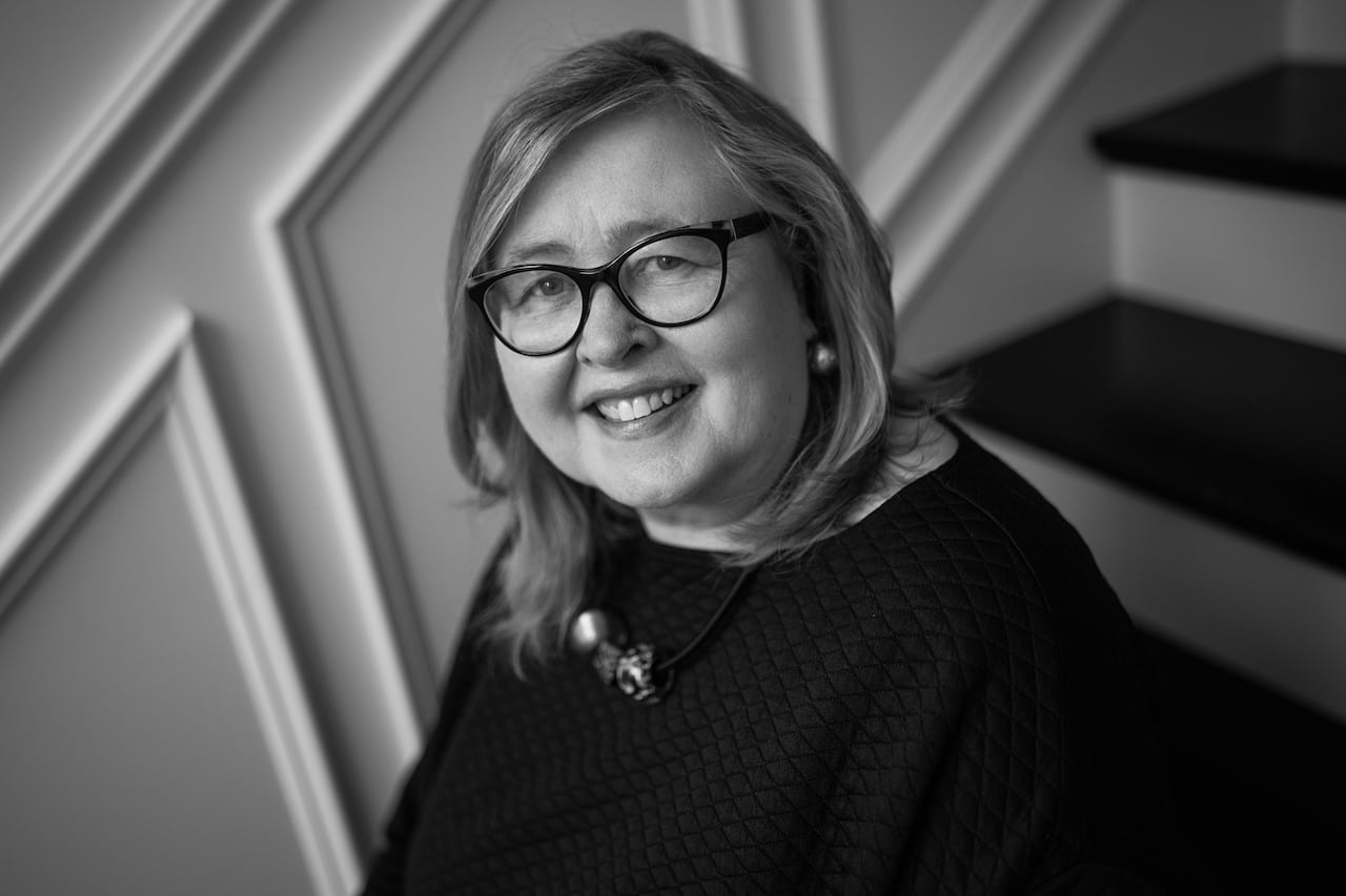 A black and white photo of a women with shoulder length hair and glasses.