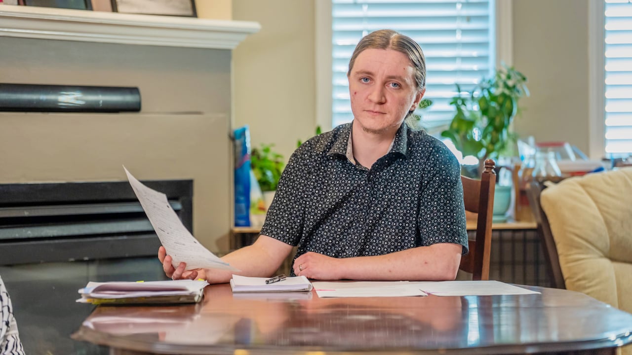 A man at a desk, holding a sheet of paper.