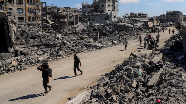 People walk through mounds of rubble.