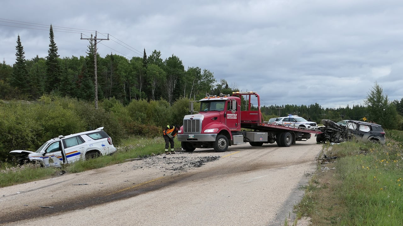 A vehicle, right, involved in a collision with an RCMP cruiser, left, is moved onto a flatbed truck on Provincial Road 304 near Black River, Man.