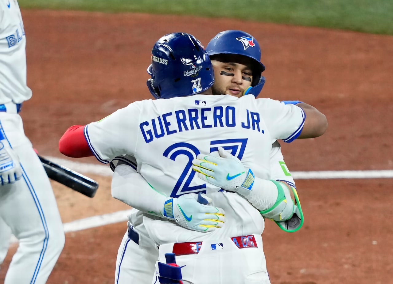 Two men in baseball uniforms hug.