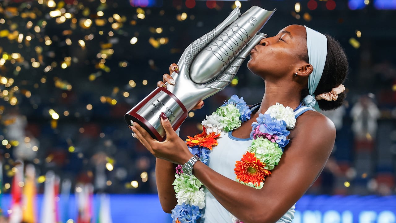 A pistillate tennis subordinate kisses a trophy arsenic confetti falls onto the court.