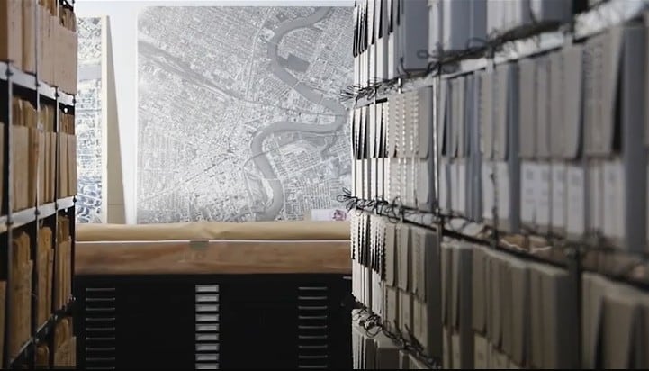 An aisle of bookshelves with documents and a map