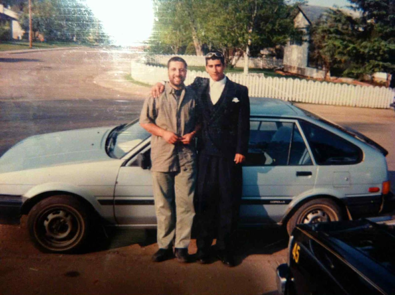 Two young men pose in front of vehicle in a Fort McMurray neighbourhood in the 1990s