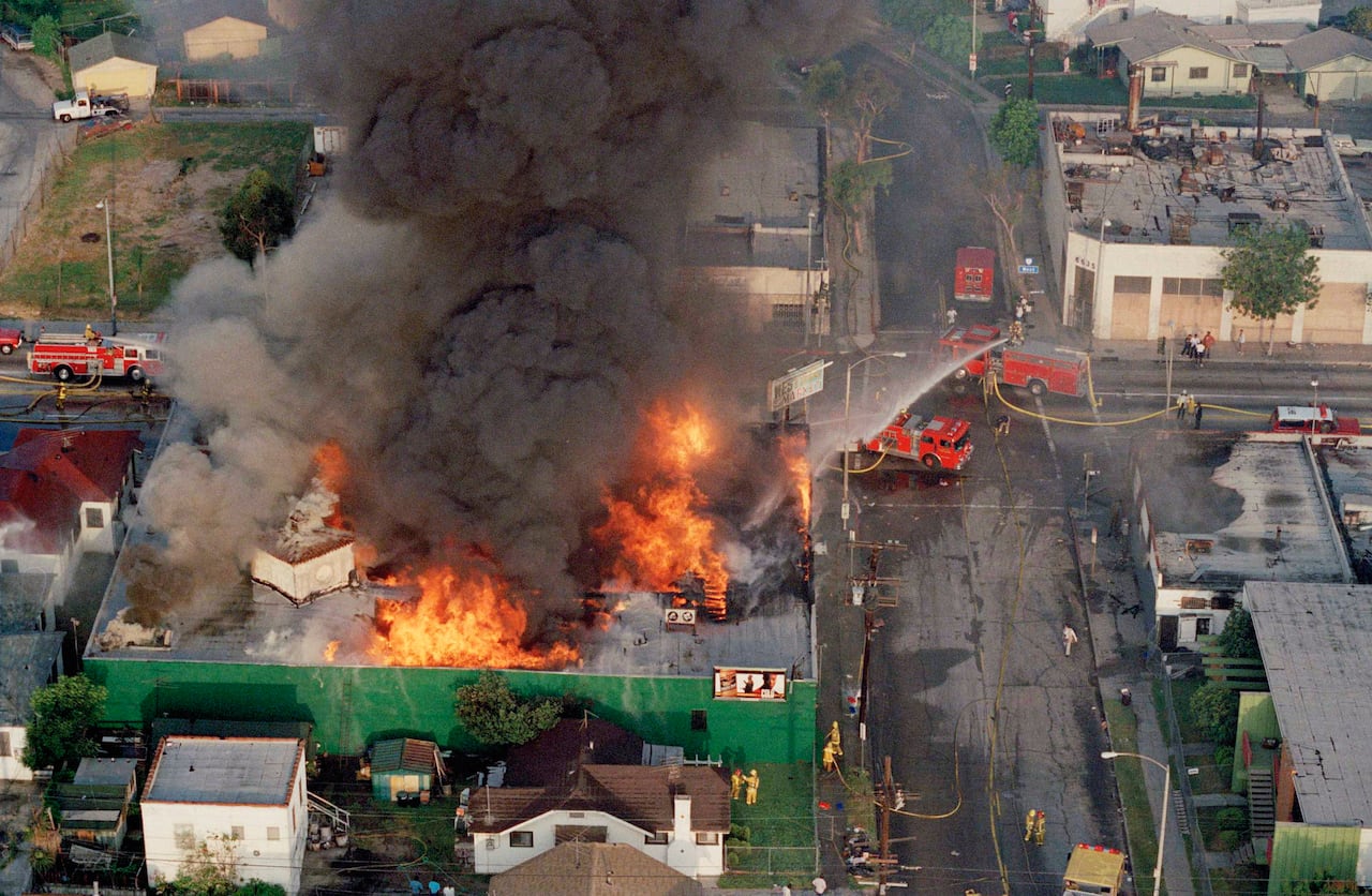 An aerial photo shows a building on a city street engulfed by a large fire.