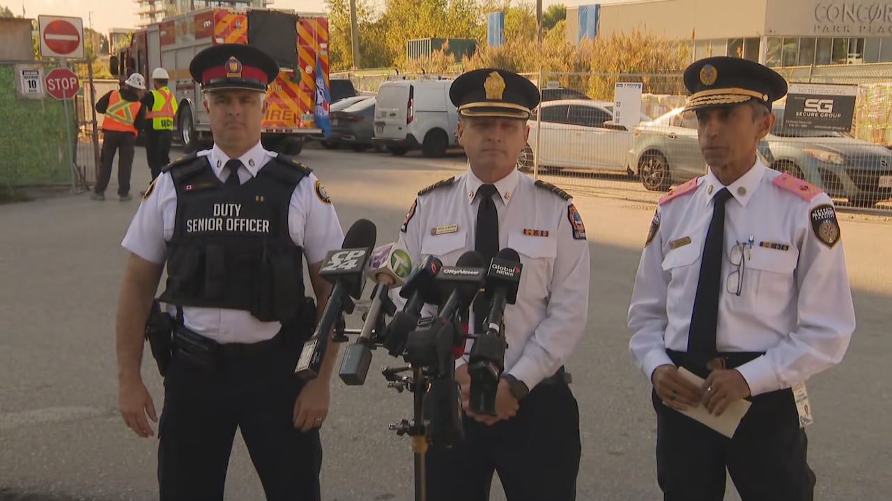 Three men in uniform stand in front of a microphone.