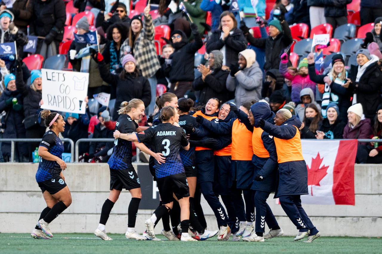 Soccer players representing the Ottawa Rapid celebrate after scoring a goal.