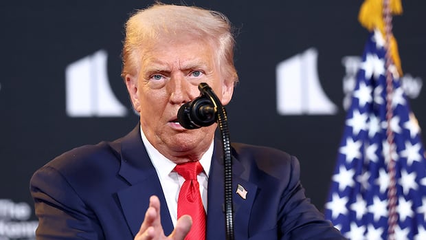 Man in blue suit speaks into microphone