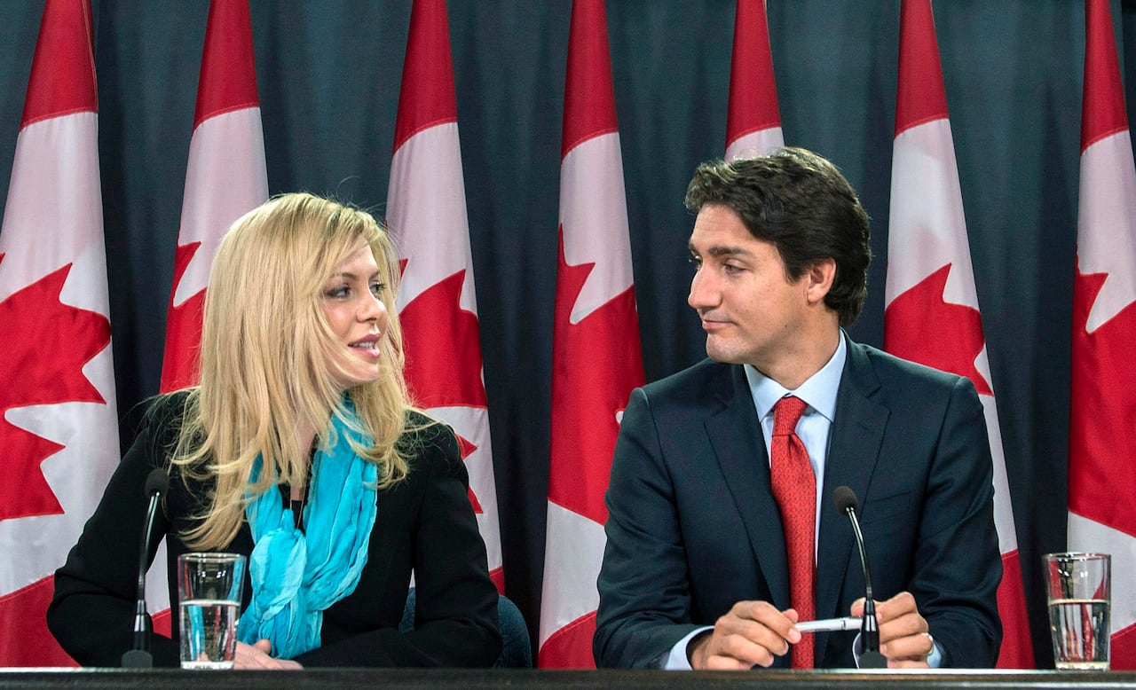 A woman smiles at a man during a press conference