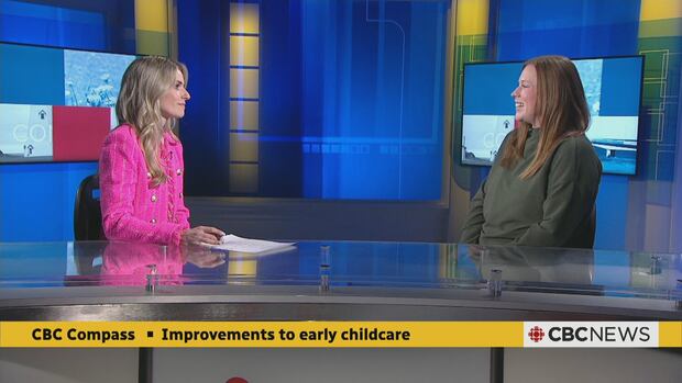 Sheehan Desjardins sits across from Jenn Nangreaves on the set of CBC News: Compass. A woman with blonde hair wearing a bright pink jacket and a brown-haired woman in a green sweater talk on a TV news set.