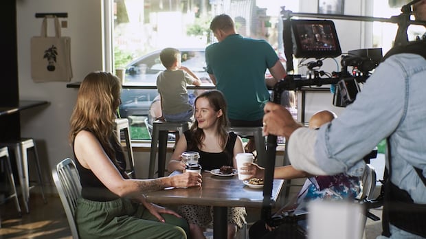 Natalie Hyttenrauch and other actors at Anchor Coffee House in Walkerville playing out a scene for a Canadian Down Syndrome Society commercial. Group sits at a table in a cafe.