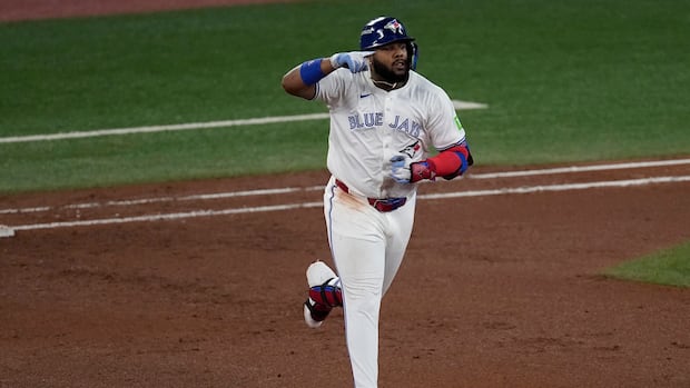 A baseball player points as he rounds the bases after hitting a home run.