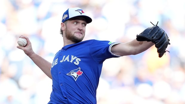 A man wearing a blue and white uniform throws a baseball.