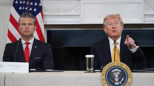 President Donald Trump answers questions from reporters during a roundtable on criminal cartels in the State Dining Room of the White House, Thursday, Oct. 23, 2025, in Washington, as Defense Secretary Pete Hegseth listen. (AP Photo/Evan Vucci) Two men in suit and tie are shown seated. A younger cleanshaven man has a stern look on his face, while an older blone haired man points.